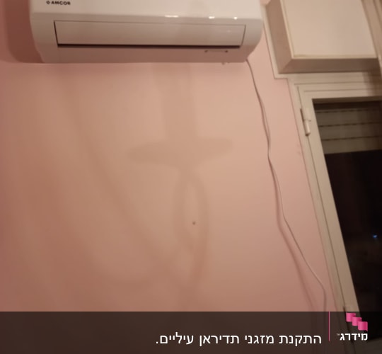 מזגן קיר לבן מותקן על קיר ורוד